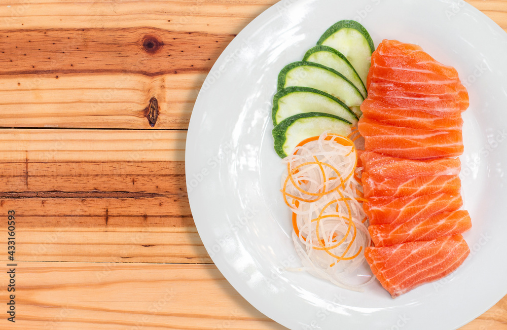 raw salmon red fish and vegetables on white plate with wooden background