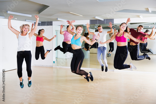 Happy sporty different ages adults jumping at dance class