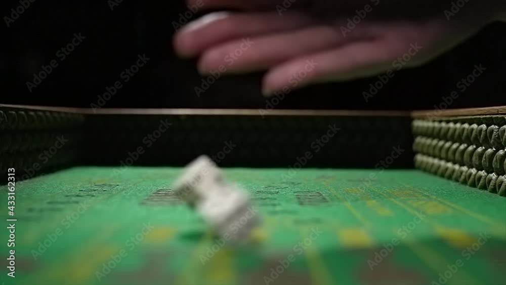 This video shows a close up, POV view of a hand rolling a pair of dice towards the camera on a green felt craps gambling table in slow motion. This video shows a close up, POV view of a hand rolling a pair of dice towards the camera on a green felt craps gambling table in slow motion.