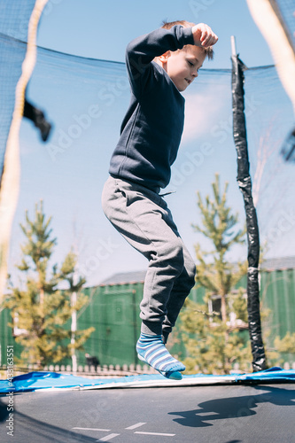 Little boy jumping in trampoline in the park. Children's leisure cooutdoors, lifestyle concept © Anikonaann