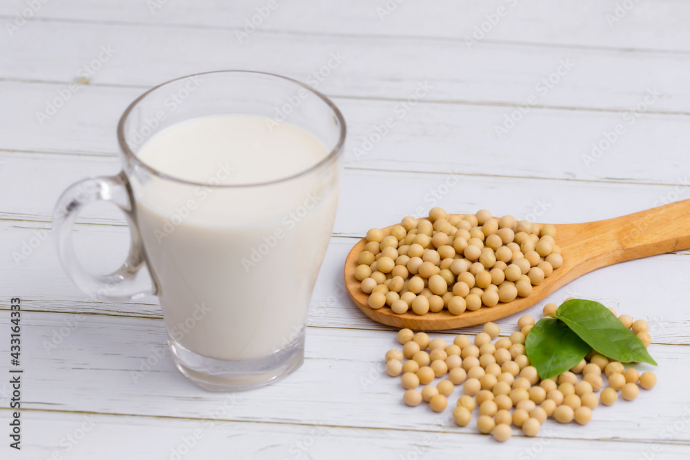 Soy and soy milk in a glass with soybeans in wooden bowl background Soy and soy milk in a glass with soybeans in wooden bowl background
