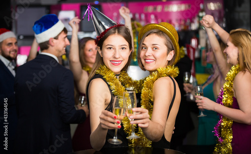 Portrait of smiling females and males in caps and garlands in the night club