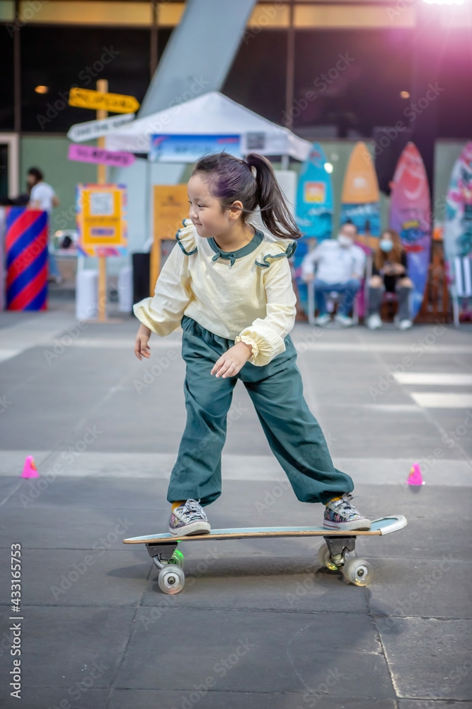 Cute little girl playing skateboard or surf skate in the urban city Cute little girl playing skateboard or surf skate in the urban city