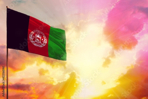 Fluttering Afghanistan flag in top left corner mockup with the space for your text on beautiful colorful sunset or sunrise background.