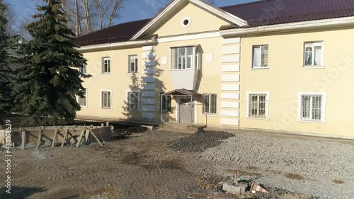 Drone view of Reconstruction of a two-story house and pedestrian boulevard in a provincial autumn town. Heaps of rubble and sand lie. Construction work in progress.
 photo