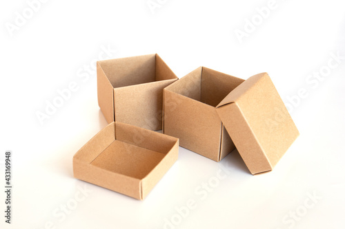 Opened brown cardboard box with lid on white background