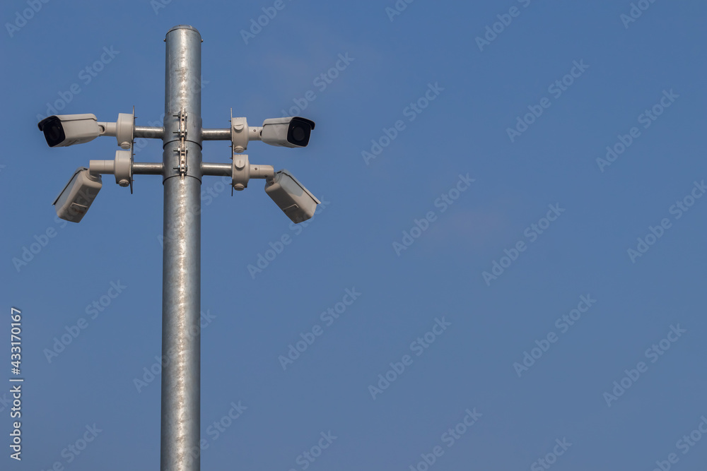 Low angle view of the surveillance security cameras on steel pole in outdoor public car parking with clear blue sky background. Low angle view of the surveillance security cameras on steel pole in outdoor public car parking with clear blue sky background.