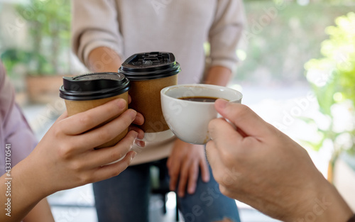 Closeup of a group of young people enjoyed drinking and clinking coffee cups together in cafe