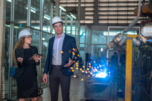 Bangkok - Thailand 06 February 2021 : Manager engineer and secretary  check welding robotics automatic arms machine in intelligent factory automotive industrial with monitoring system software. Weldin
