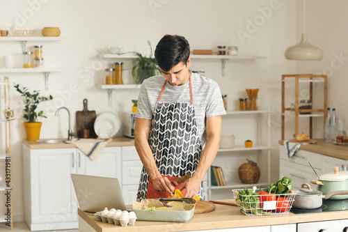 Young man cutting fresh pep...