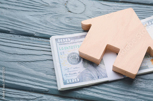 Foto Figure of house and dollar banknote on color wooden background