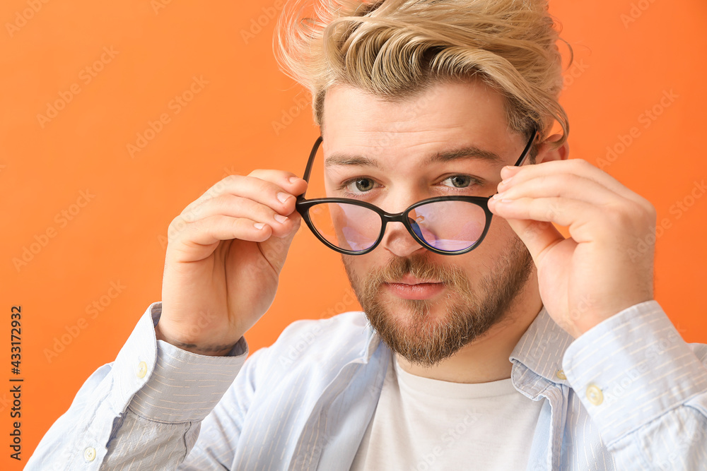 Young man wearing eyeglasses on color background