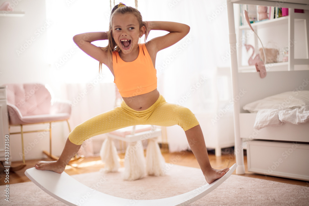 Little girl doing a workout in the bedroom at home. Stock Photo