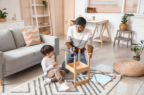 Canvas Print Father and little son fixing chair at home