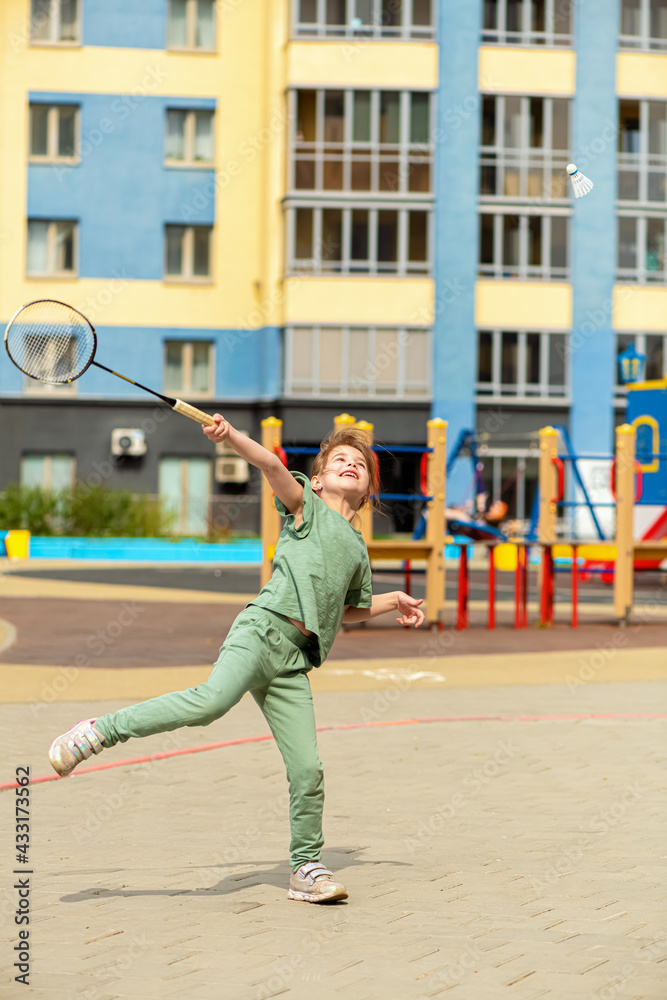 Cute little girl plays in the yard in badminton