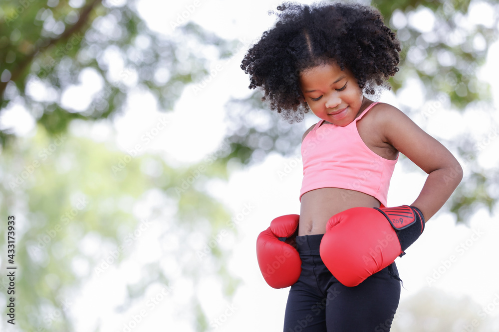 Fototapeta premium childhood and people concept - little african american curly hair girl wear gym clothes and red boxing gloves,looking down beautiful shape.