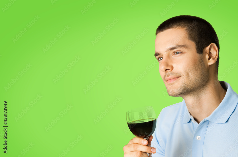 Portrait of thinking man with glass of wine, looking forward, isolated over green color background with copy space for some slogan or text. Portrait of thinking man with glass of wine, looking forward, isolated over green color background with copy space for some slogan or text.