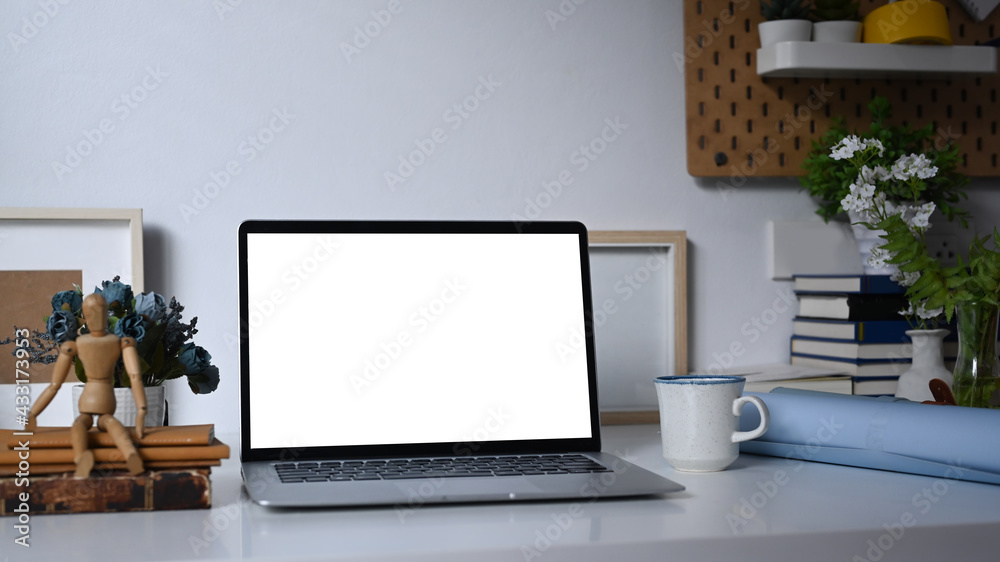 A computer laptop with empty screen and office supplies on white table. A computer laptop with empty screen and office supplies on white table.