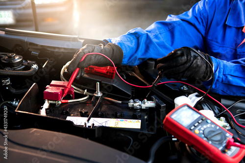 Technician uses multimeter voltmeter to check voltage level in car battery. Service and Maintenance car battery.