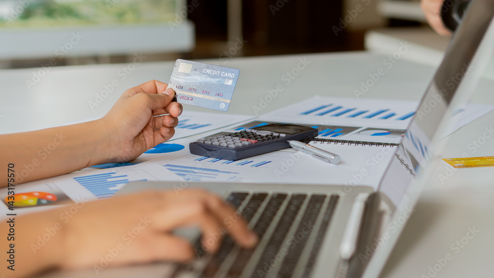 Business women hold credit cards and use laptop computers and mobile phones to shop online, e-commerce, internet banking, spend money, work from home.