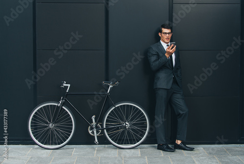 Handsome young business man with his modern bicycle.