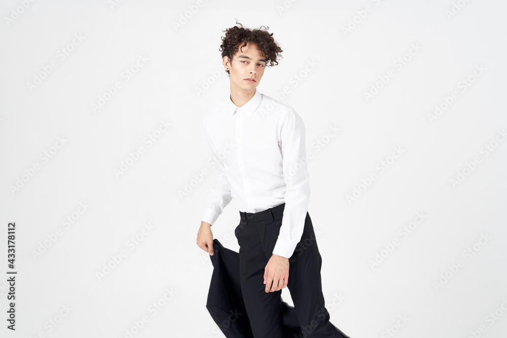 young man with curly hair and in a classic suit holds a jacket in his hand fashion style photography studio model young man with curly hair and in a classic suit holds a jacket in his hand fashion style photography studio model