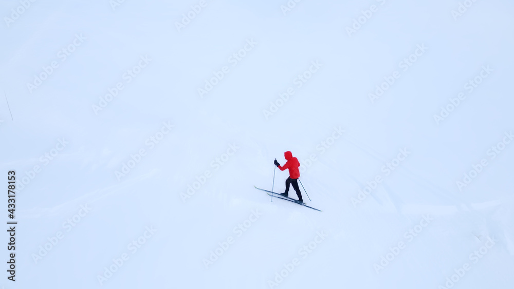 Cross country skier traveling across a snow covered arctic tundra in the high mountains on a cold winters day.