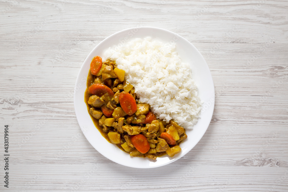 Homemade Japanese Chicken Curry  on a white plate on a white wooden background, top view. Flat lay, overhead, from above.