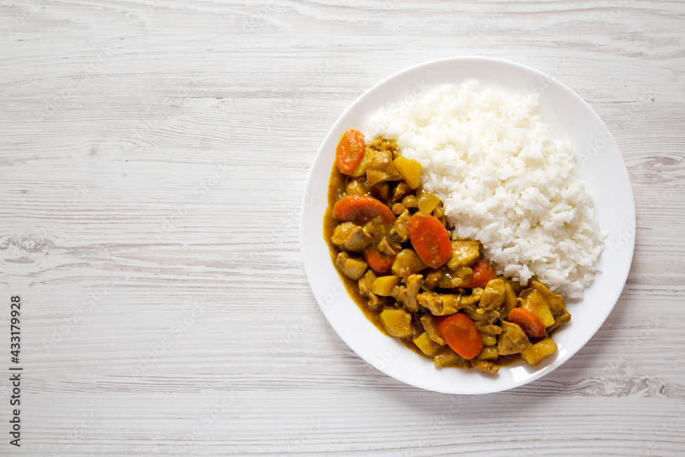 Homemade Japanese Chicken Curry on a white plate on a white wooden background, top view. Flat lay, overhead, from above. Copy space. Homemade Japanese Chicken Curry on a white plate on a white wooden background, top view. Flat lay, overhead, from above. Copy space.