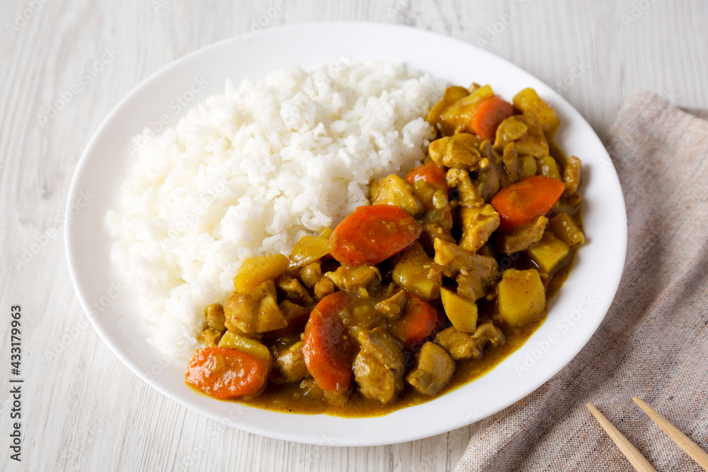 Homemade Japanese Chicken Curry on a white plate on a white wooden background, side view. Homemade Japanese Chicken Curry on a white plate on a white wooden background, side view.