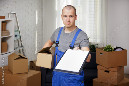 delivery and moving day concept - handsome loader holding clipboard in apartment © Di Studio