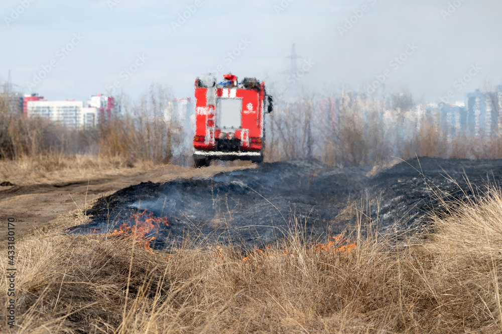 Fototapeta premium Burning vegetation in the meadows under the control of the fire department near the city