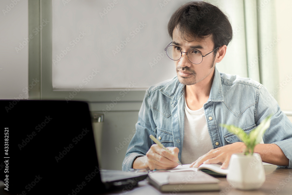 young man watching at laptop and writing on notebook while stay at home, online lerning and work from home young man watching at laptop and writing on notebook while stay at home, online lerning and work from home