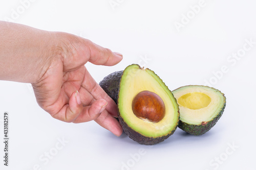 Hand touching an avocado cut in half: Selective focus and close up. Healthy food concept.