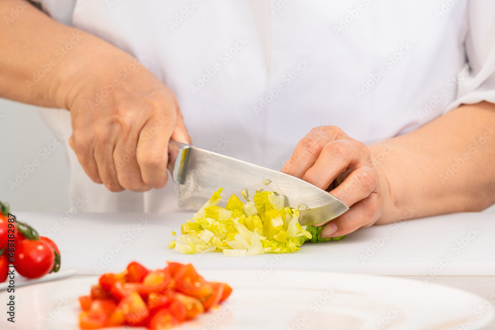 Hands cutting fresh lettuce with a knife on a cutting board