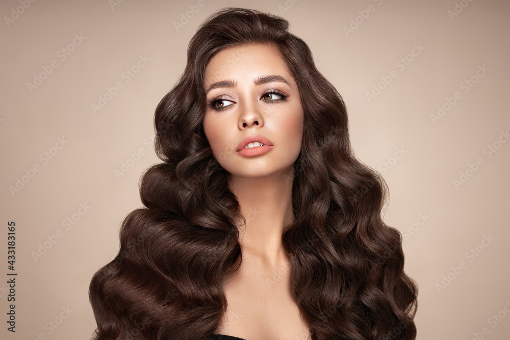 Naklejka premium Brunette girl with perfect makeup. Smiling beautiful model woman with long curly hairstyle. Care and beauty hair products.