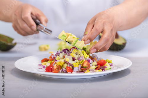Putting avocado dice on a delicious salad