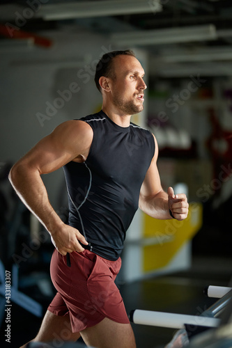 Male athlete jogging on treadmill during gym workout.