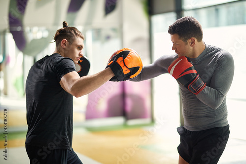 Two athletic man practicing boxing on sports training in a gym. © Drazen