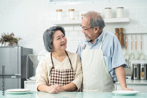 Asian grandparents couple smiling looking at each other in the kitchen