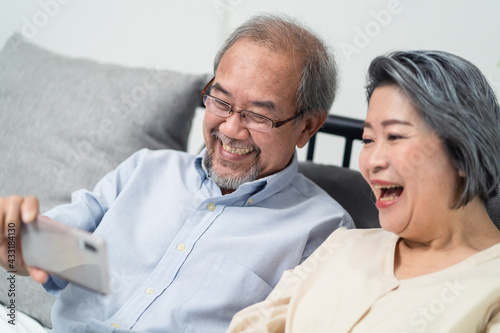 Asian senior couple making video call via smartphone with their child.