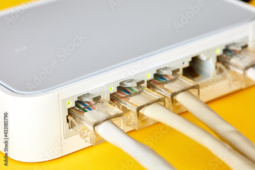 Ethernet cables connected to Desktop Switch or routerboard on a yellow background. Close-up, selective focus photo