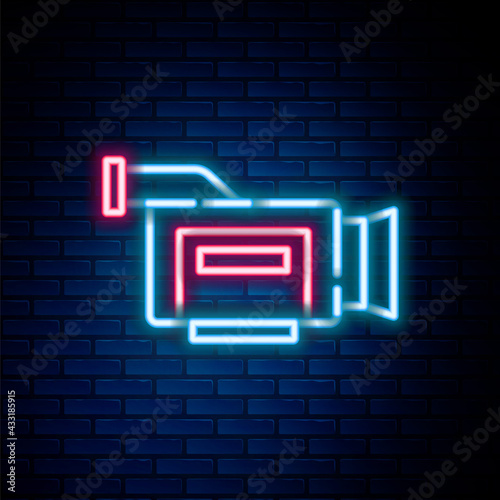 Glowing neon line Cinema camera icon isolated on brick wall background. Video camera. Movie sign. Film projector. Colorful outline concept. Vector