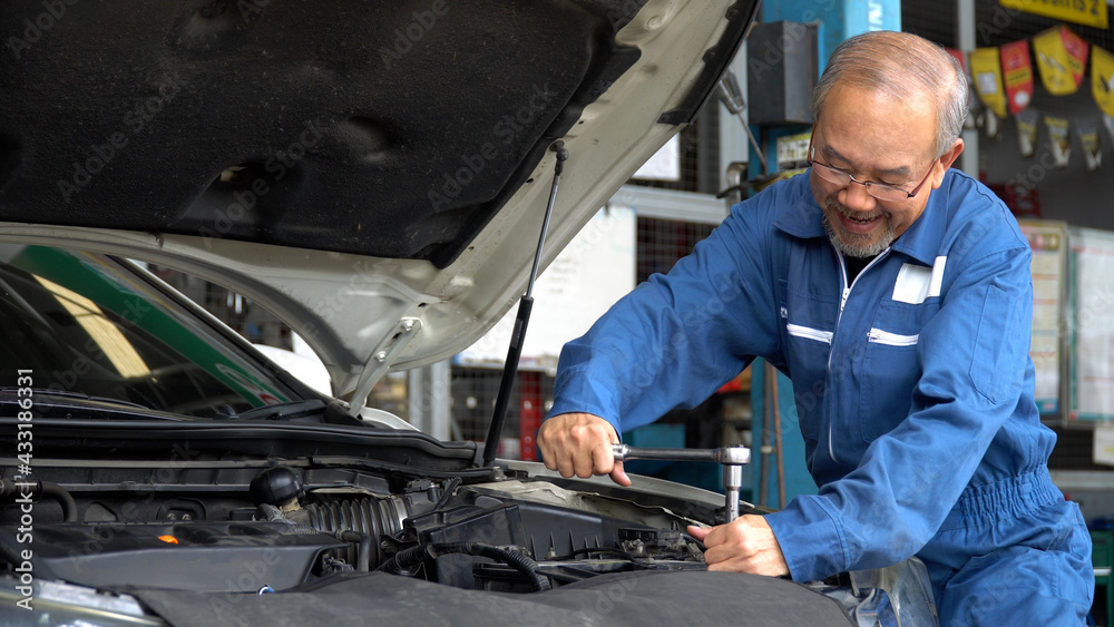 asian mechanic senior man using socket spanner wrench repairing a car in workshop at auto car repair service center. car engineer old man inspection vehicle details asian mechanic senior man using socket spanner wrench repairing a car in workshop at auto car repair service center. car engineer old man inspection vehicle details