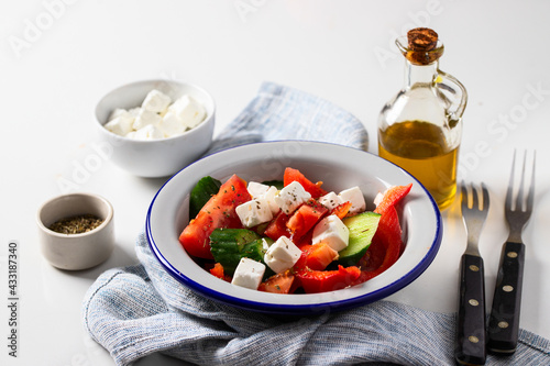 Healthy salad made from  vegetable feta cheese  cucumber  tomato  sweet pepper   and dressing with olive oil and spices in rustic bowl on white background
