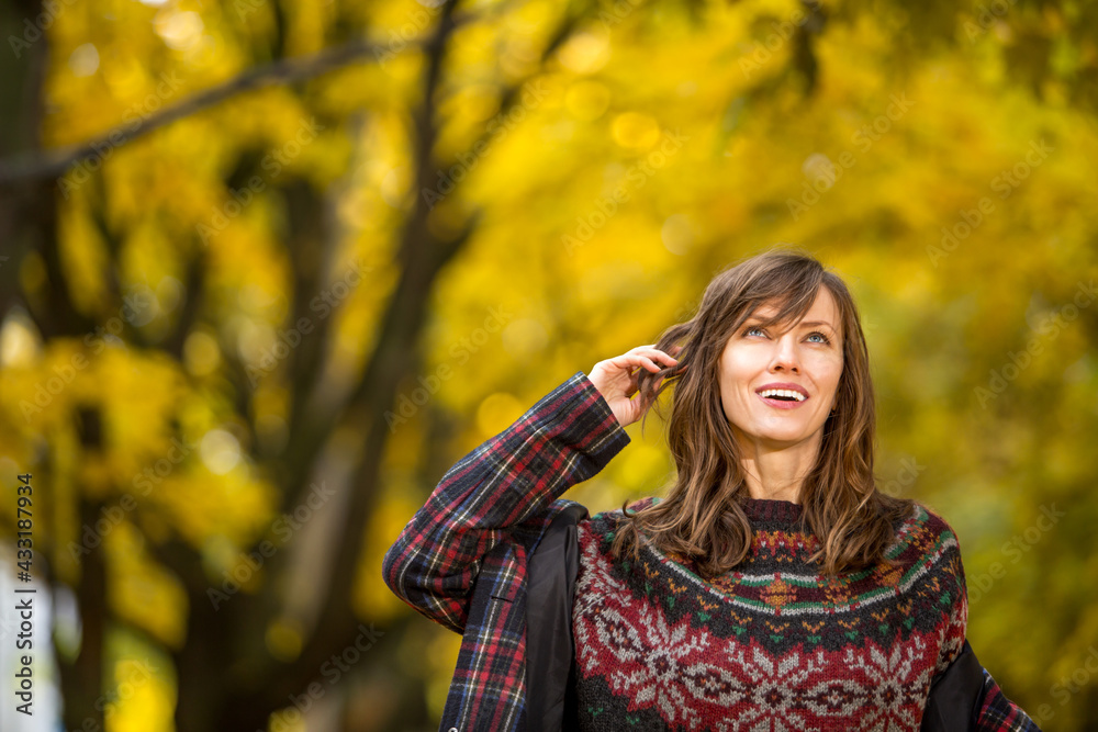 portrait of beautiful woman wearing sweater in autumn yellow park	