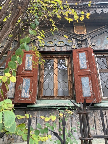 Old window in the house. Ancient wooden Russian peasant's house of 19 century. Window with carved shutters in old cottage.