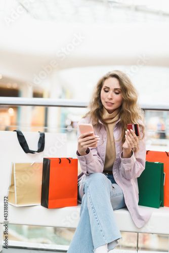 A young woman shopping in an online store pays with a credit card online. Shopaholic concept.