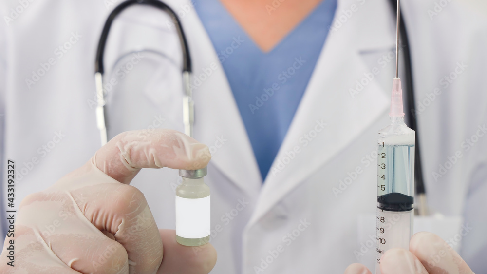 Selective focus of Doctor's hand holds a syringe vaccine bottle at the hospital. Health and medical concepts Selective focus of Doctor's hand holds a syringe vaccine bottle at the hospital. Health and medical concepts