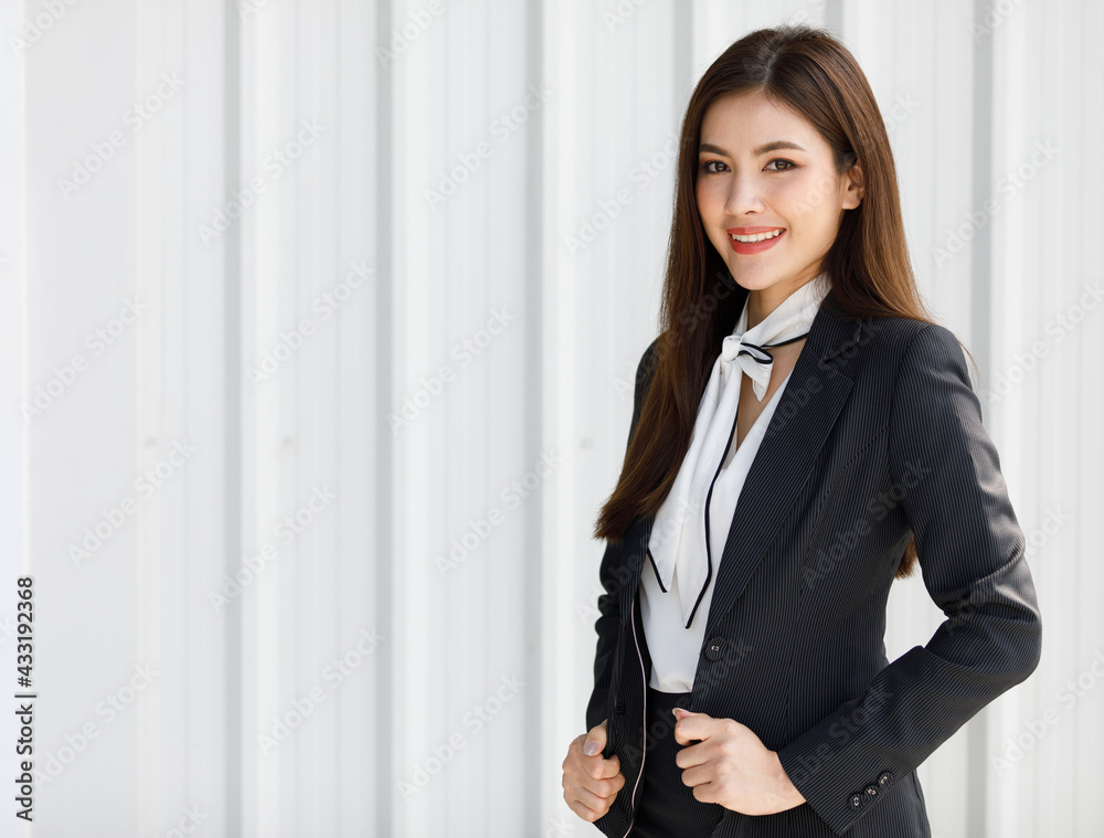 Asian woman standing half length in black suit. Businesswoman holding in business formal suit standing in office room..Concept Beautiful and confident working woman. Asian woman standing half length in black suit. Businesswoman holding in business formal suit standing in office room..Concept Beautiful and confident working woman.